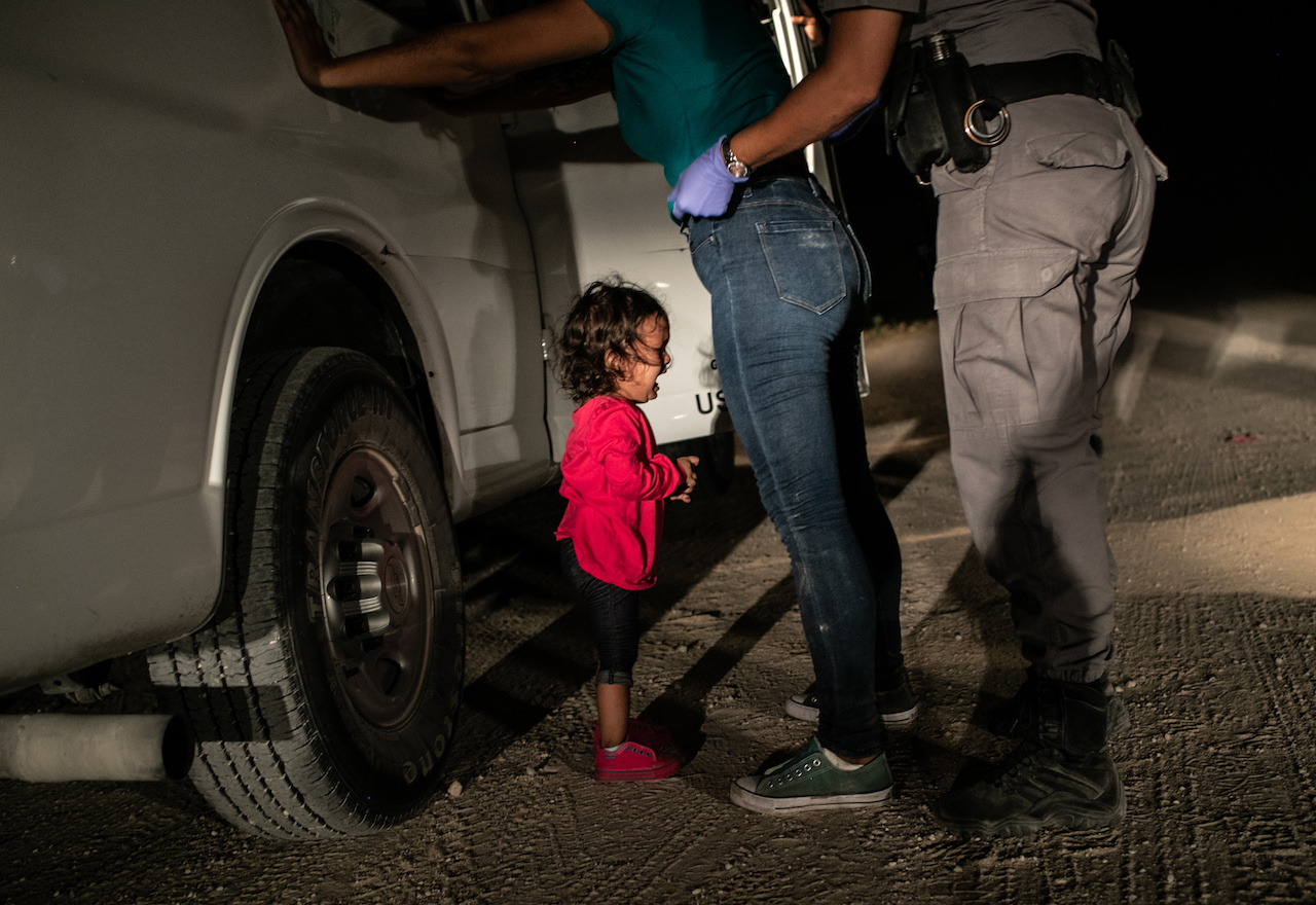 A two-year-old Honduran asylum seeker cries as her mother is searched and detained near the U.S.-Mexico border by John Moore of Getty Images